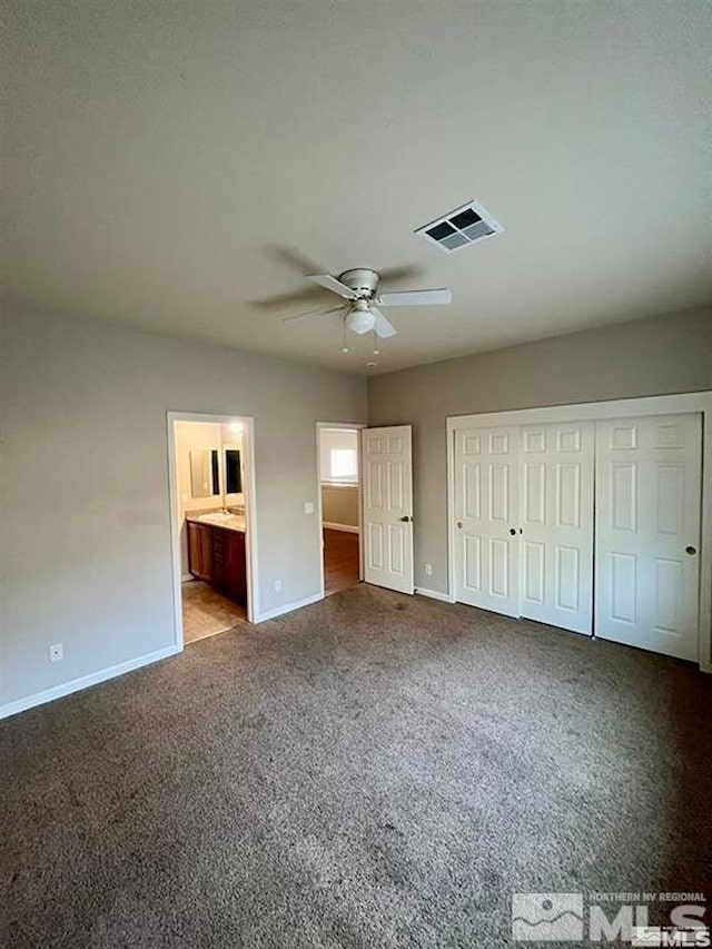 unfurnished bedroom featuring a closet, ensuite bathroom, light carpet, and ceiling fan