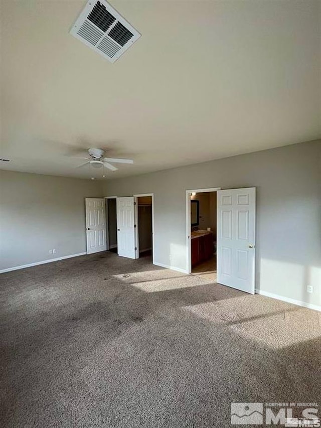 unfurnished bedroom featuring carpet, ensuite bathroom, and ceiling fan