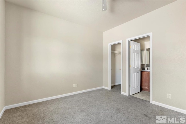 unfurnished bedroom featuring light carpet, a closet, and a spacious closet