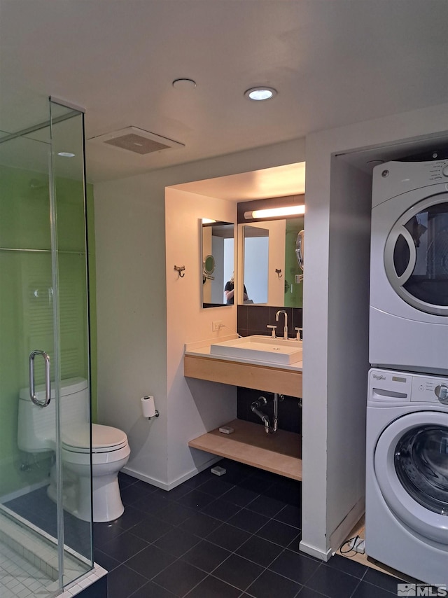 bathroom featuring stacked washing machine and dryer, tile patterned floors, baseboards, and a shower stall