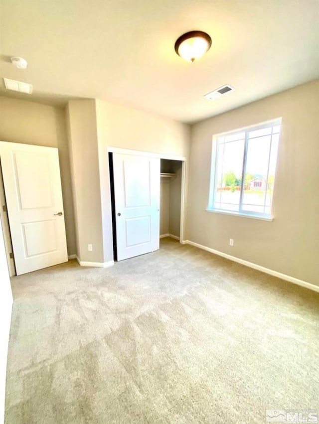 unfurnished bedroom featuring light carpet and a closet