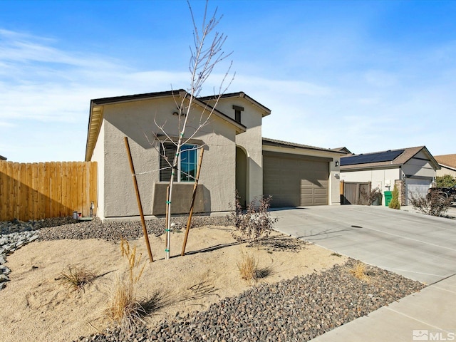 view of front of home with stucco siding, fence, concrete driveway, and a garage