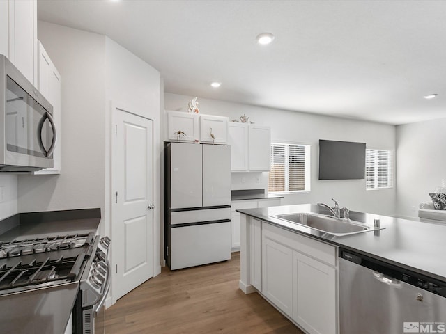 kitchen featuring a sink, light wood-style flooring, white cabinets, appliances with stainless steel finishes, and recessed lighting