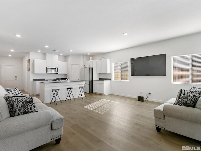 living area with baseboards, light wood-style flooring, visible vents, and recessed lighting