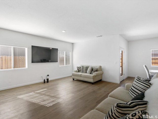 living room featuring wood finished floors, visible vents, and baseboards