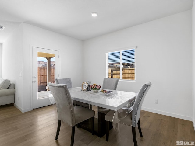 dining area with baseboards, visible vents, and light wood finished floors