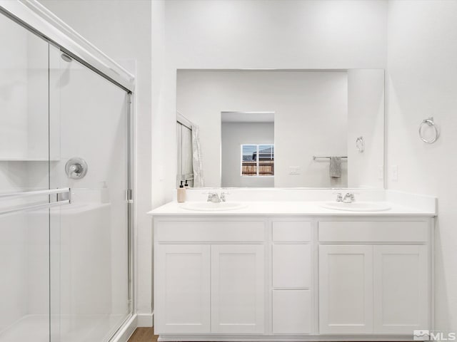 full bath with a sink, double vanity, and a stall shower