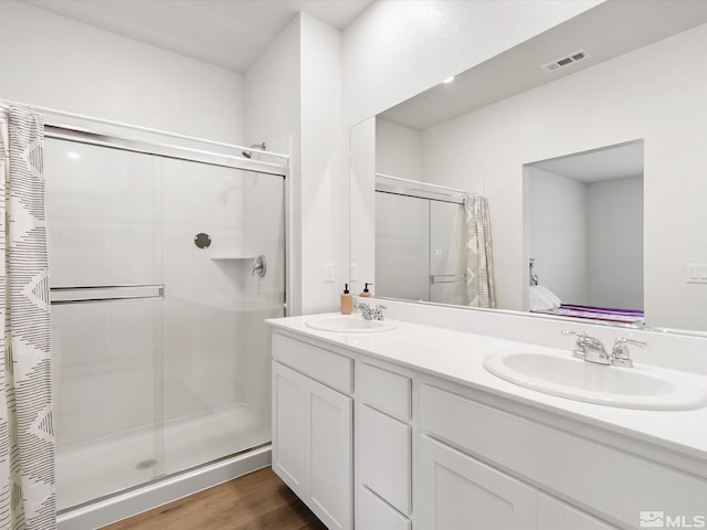 full bathroom featuring visible vents, a sink, a shower stall, and double vanity