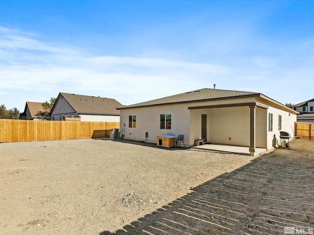 rear view of property with a fenced backyard, central AC, a patio, and stucco siding