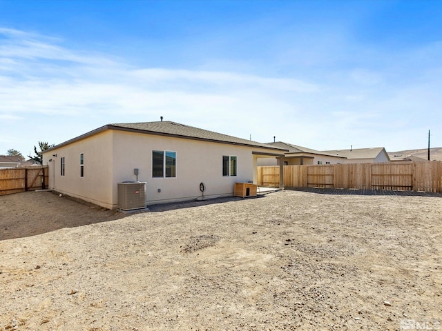 rear view of property with stucco siding, a fenced backyard, and central AC unit