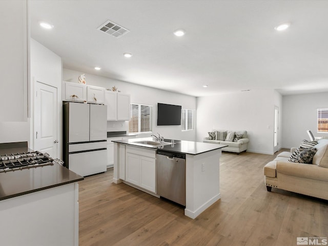 kitchen featuring stainless steel dishwasher, a sink, open floor plan, visible vents, and freestanding refrigerator