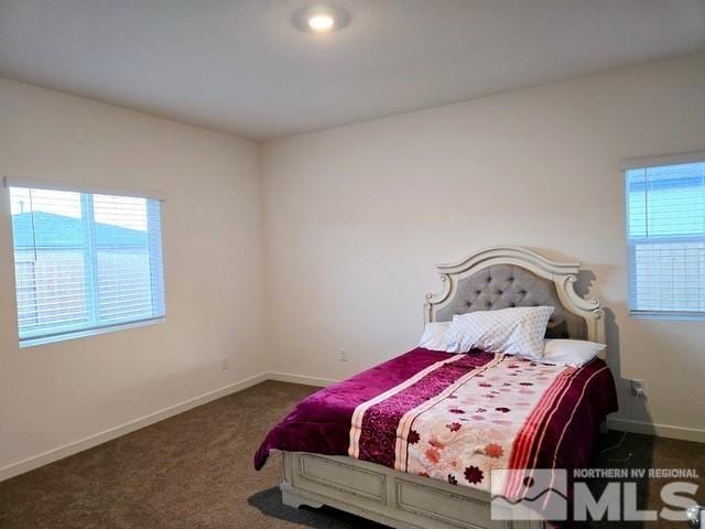 bedroom with dark colored carpet and multiple windows