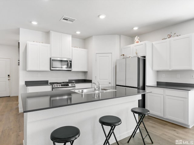 kitchen featuring dark countertops, visible vents, appliances with stainless steel finishes, and a sink