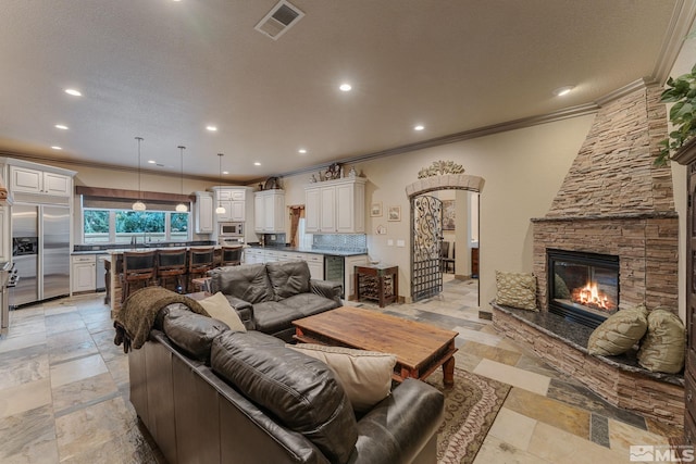 living room with beverage cooler, a fireplace, ornamental molding, and a textured ceiling