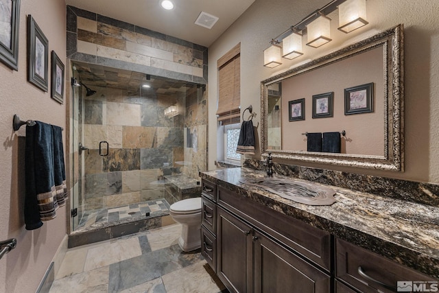 bathroom with a shower with shower door, vanity, and toilet