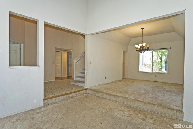 carpeted empty room with vaulted ceiling and a notable chandelier