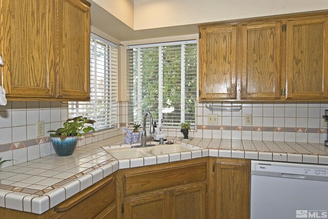 kitchen with dishwasher, tile countertops, sink, and decorative backsplash