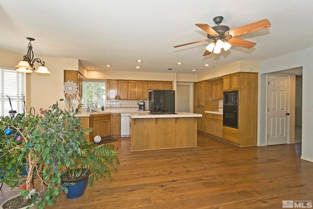 kitchen featuring ceiling fan with notable chandelier, black appliances, plenty of natural light, and dark wood-type flooring