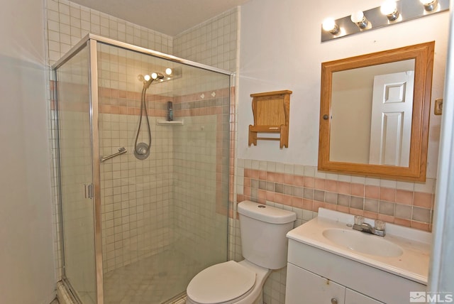 bathroom with tile walls, an enclosed shower, vanity, and toilet