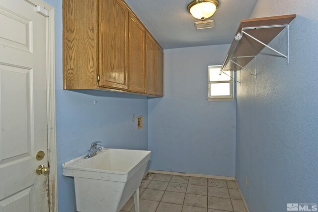 laundry area with washer hookup, light tile patterned floors, sink, a textured ceiling, and cabinets