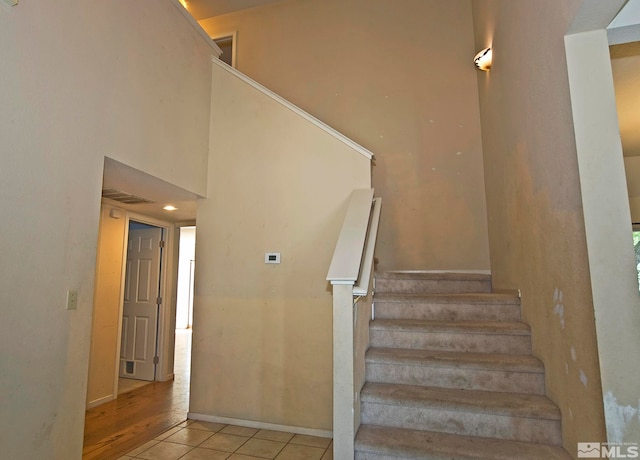 staircase with a towering ceiling and hardwood / wood-style flooring