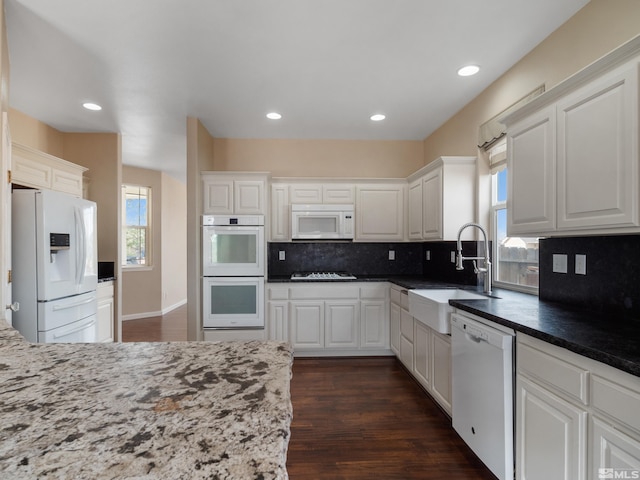 kitchen with sink, white appliances, backsplash, dark wood-type flooring, and white cabinetry