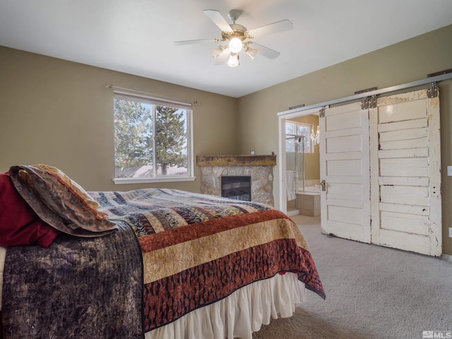 bedroom featuring a barn door, connected bathroom, ceiling fan, and carpet floors