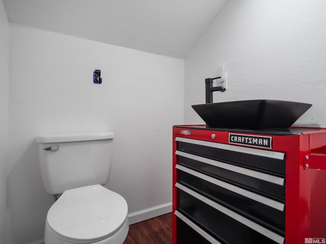 bathroom featuring vanity, hardwood / wood-style flooring, lofted ceiling, and toilet