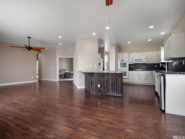 kitchen featuring white appliances, a center island, ceiling fan, and dark wood-type flooring