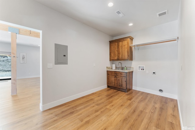 clothes washing area with a sink, washer hookup, hookup for an electric dryer, baseboards, and light wood-style floors
