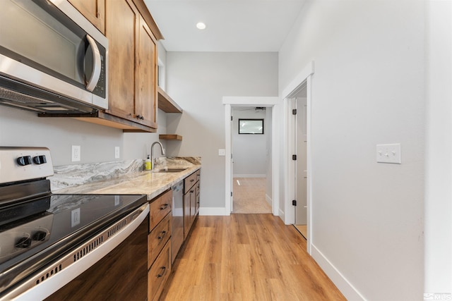 kitchen with light wood finished floors, baseboards, light stone countertops, brown cabinets, and appliances with stainless steel finishes