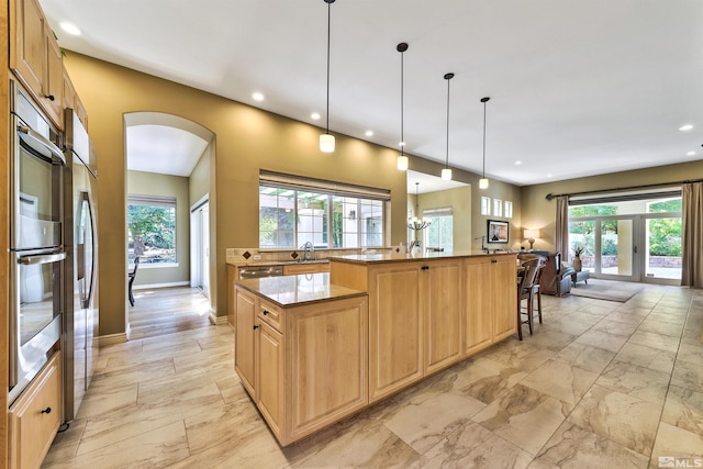 kitchen featuring a breakfast bar, sink, an island with sink, hanging light fixtures, and french doors