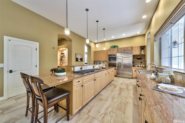 kitchen featuring pendant lighting, sink, kitchen peninsula, appliances with stainless steel finishes, and a kitchen bar