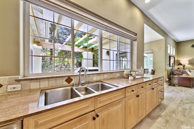 kitchen featuring light stone counters, light brown cabinets, sink, and decorative backsplash