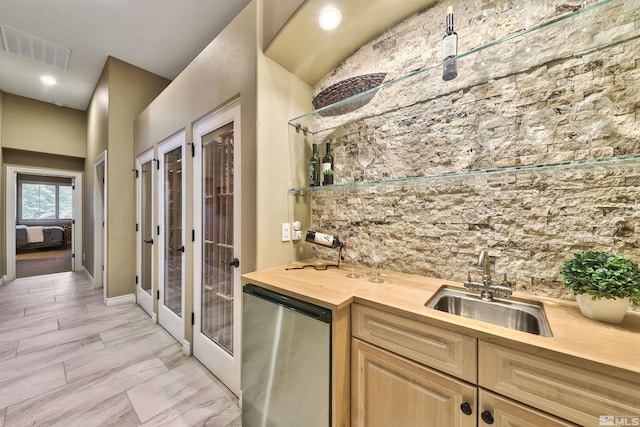 kitchen featuring light brown cabinetry, stainless steel dishwasher, sink, and butcher block counters