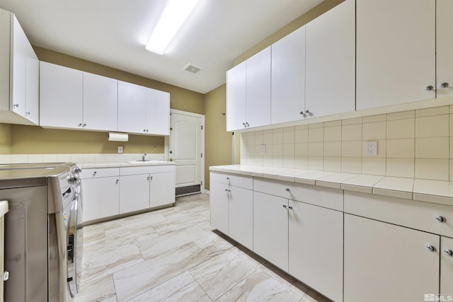 kitchen with white cabinetry, washing machine and clothes dryer, and tasteful backsplash