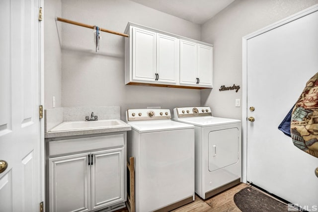 laundry room with light wood-type flooring, washing machine and dryer, sink, and cabinets