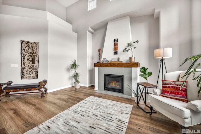 sitting room with a high ceiling, hardwood / wood-style flooring, and a fireplace