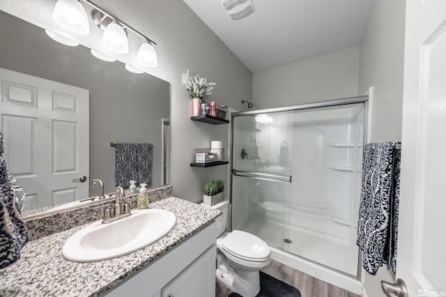 bathroom with wood-type flooring, vanity, toilet, and an enclosed shower