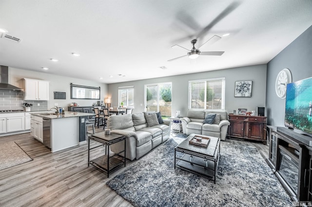 living room featuring light hardwood / wood-style floors, ceiling fan, and sink