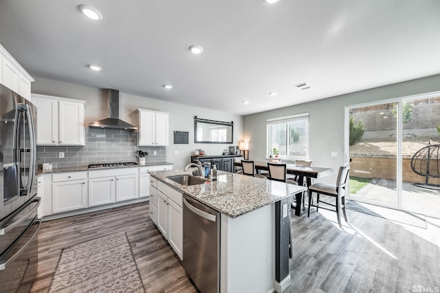 kitchen featuring white cabinetry, stainless steel appliances, hardwood / wood-style flooring, sink, and wall chimney range hood