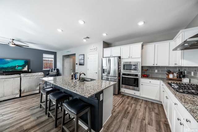 kitchen featuring appliances with stainless steel finishes, a kitchen breakfast bar, white cabinets, light stone countertops, and ceiling fan