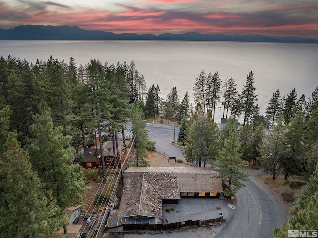 aerial view at dusk featuring a water and mountain view