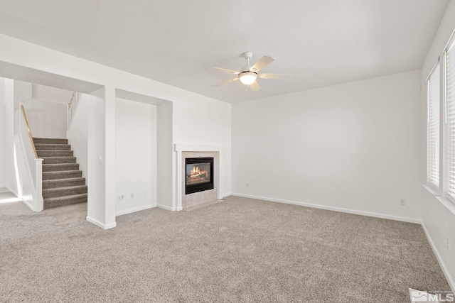 unfurnished living room with ceiling fan, a fireplace, and carpet