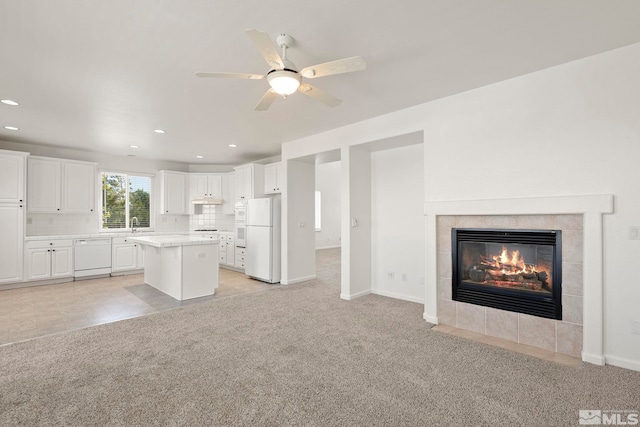 interior space featuring light carpet, ceiling fan, and a tile fireplace