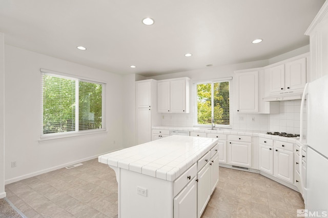 kitchen with white fridge, decorative backsplash, tile countertops, and white cabinets