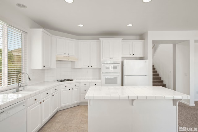 kitchen featuring white cabinets, white appliances, and tile countertops