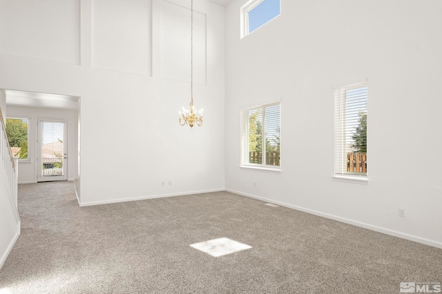 empty room with a towering ceiling, light colored carpet, and a healthy amount of sunlight