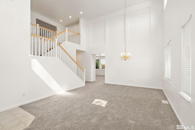 unfurnished living room with a notable chandelier, a high ceiling, and carpet