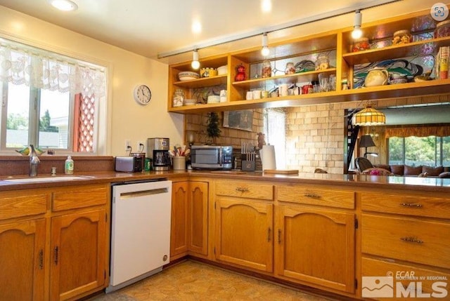 kitchen with tasteful backsplash, sink, white dishwasher, and a wealth of natural light